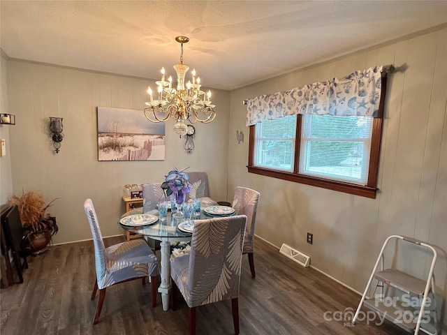 dining space with visible vents, wood walls, wood finished floors, a chandelier, and baseboards