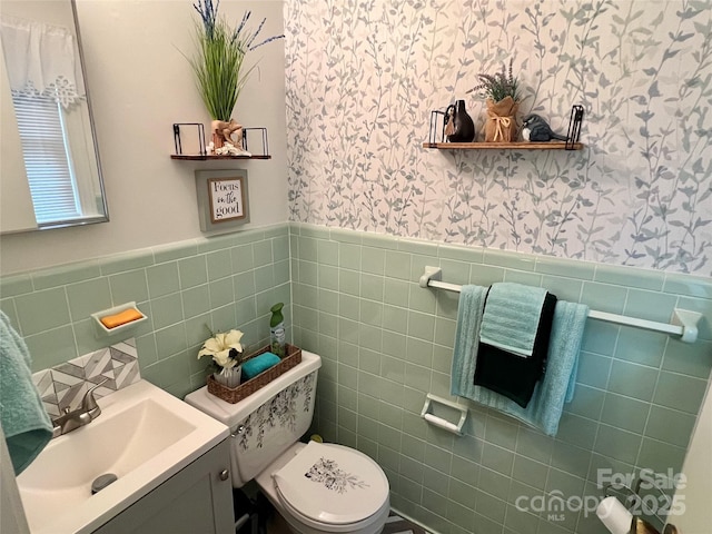 bathroom with a wainscoted wall, vanity, toilet, and wallpapered walls