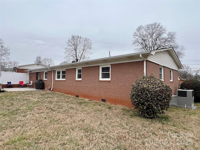 view of side of property featuring brick siding, a yard, a patio, central air condition unit, and crawl space