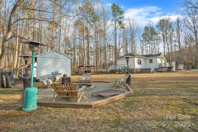 view of yard featuring a storage unit and an outdoor fire pit