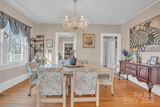 dining area featuring crown molding, an inviting chandelier, and light hardwood / wood-style floors