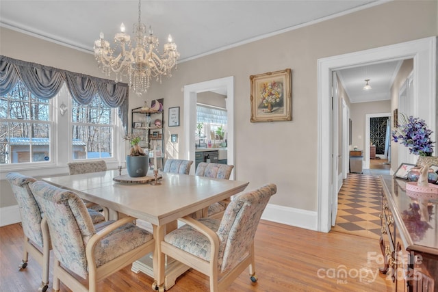 dining space featuring crown molding, an inviting chandelier, and light wood-type flooring