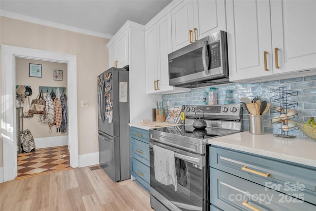 kitchen featuring appliances with stainless steel finishes, white cabinets, backsplash, crown molding, and light hardwood / wood-style flooring