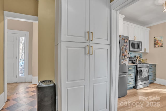 kitchen with crown molding, appliances with stainless steel finishes, backsplash, light hardwood / wood-style floors, and white cabinets