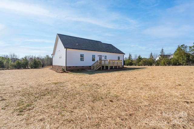 rear view of house with a wooden deck and a lawn