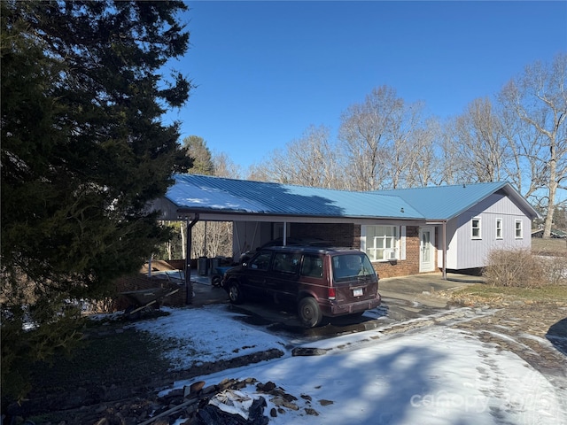 view of front facade with a carport, brick siding, and metal roof