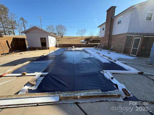 view of swimming pool featuring a fenced in pool, an outbuilding, and fence