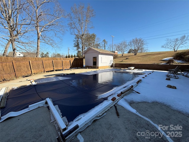 view of swimming pool featuring a storage shed, a fenced backyard, a fenced in pool, and an outbuilding