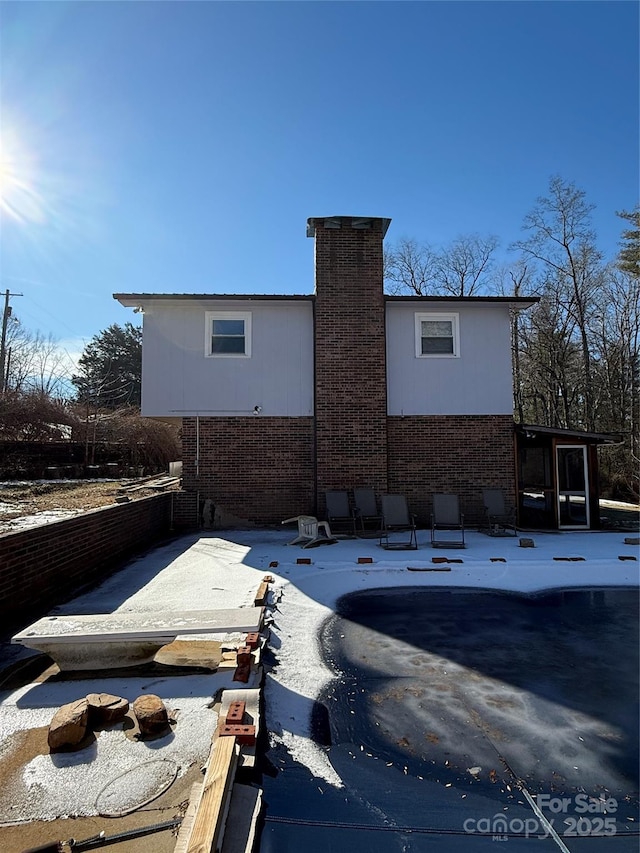 back of house with a patio, brick siding, and a chimney