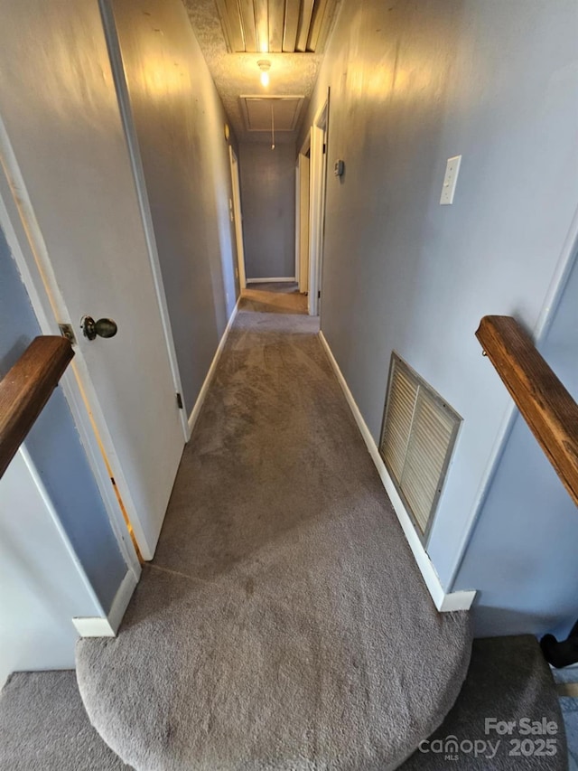 hall featuring carpet, attic access, visible vents, and baseboards