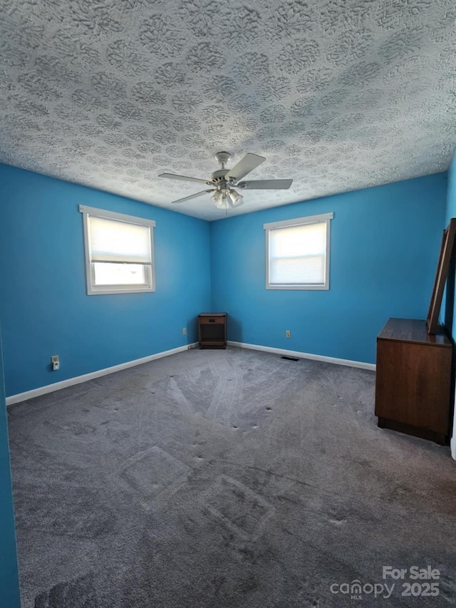 unfurnished room with a textured ceiling, ceiling fan, carpet flooring, and baseboards