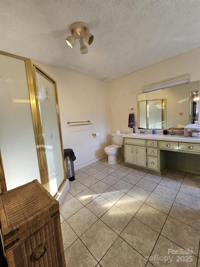 bathroom with toilet, a shower stall, a textured ceiling, vanity, and tile patterned floors