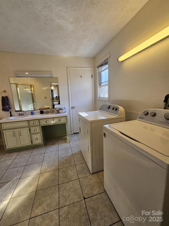 laundry room featuring light tile patterned floors, a sink, a textured ceiling, separate washer and dryer, and laundry area