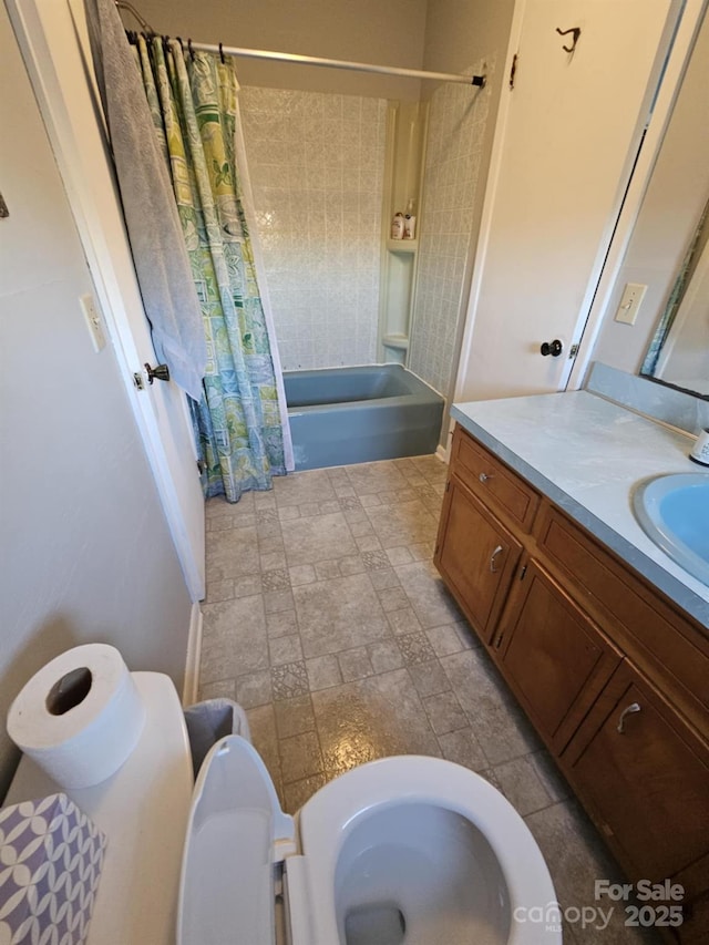 full bathroom with toilet, stone finish floor, shower / bath combo with shower curtain, and vanity