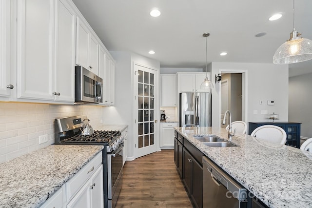 kitchen with white cabinets, stainless steel appliances, a sink, dark wood-style flooring, and light stone countertops