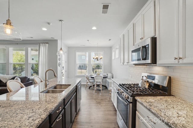 kitchen featuring stainless steel appliances, wood finished floors, visible vents, a healthy amount of sunlight, and a sink