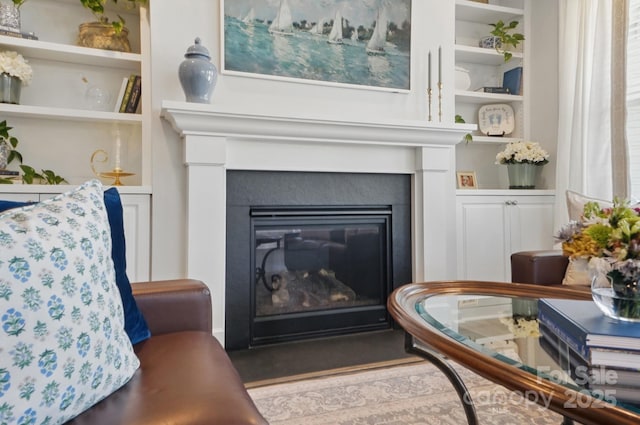 interior space with a fireplace with flush hearth, wood finished floors, and built in shelves