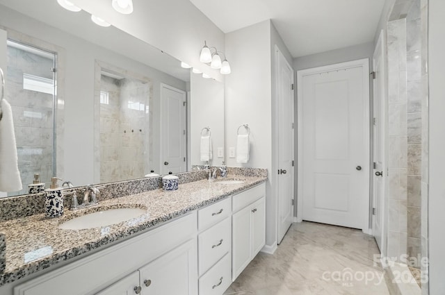 full bathroom featuring marble finish floor, a sink, double vanity, and a tile shower