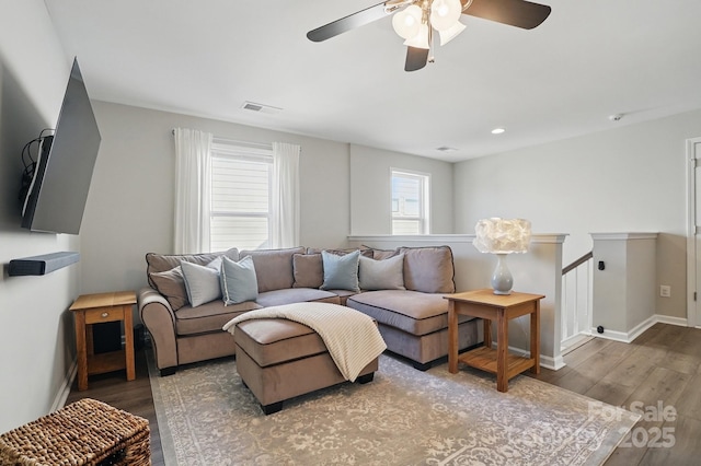 living room featuring baseboards, wood finished floors, visible vents, and ceiling fan