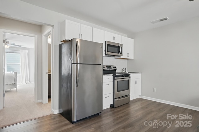 kitchen with dark wood-style floors, stainless steel appliances, visible vents, decorative backsplash, and white cabinetry