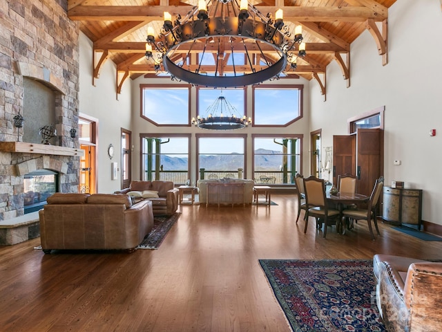 living room featuring a stone fireplace, hardwood / wood-style flooring, a mountain view, wooden ceiling, and an inviting chandelier