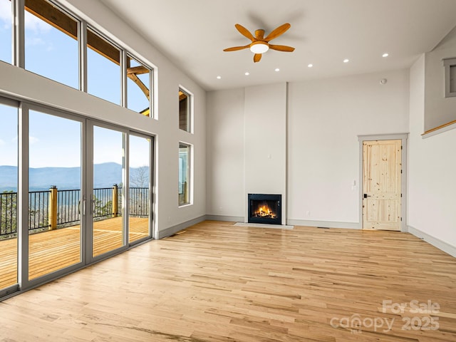 246 Half Moon Mile, Lake Lure, NC 28746 - unfurnished living room with a high ceiling, a ceiling fan, a water view, healthy amount of natural light, and light wood-style flooring