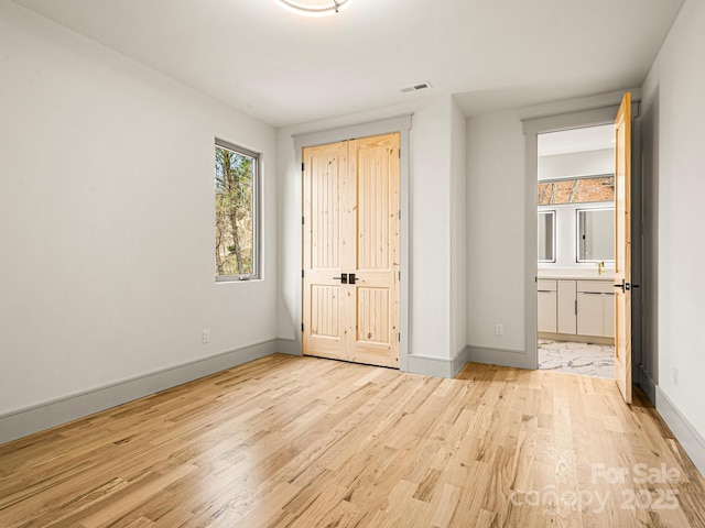 246 Half Moon Mile, Lake Lure, NC 28746 - unfurnished bedroom featuring light wood finished floors, baseboards, a closet, and ensuite bathroom