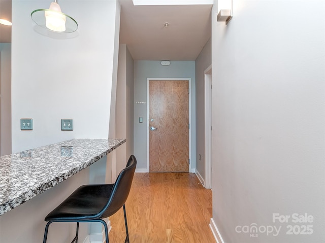 corridor with light wood-style flooring and baseboards