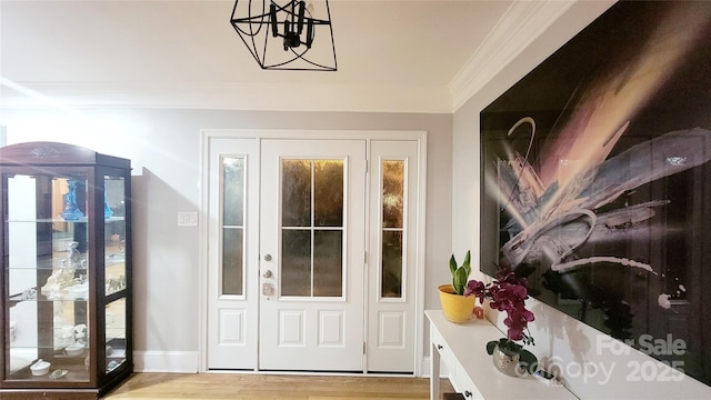 entryway featuring crown molding, a chandelier, and light hardwood / wood-style floors