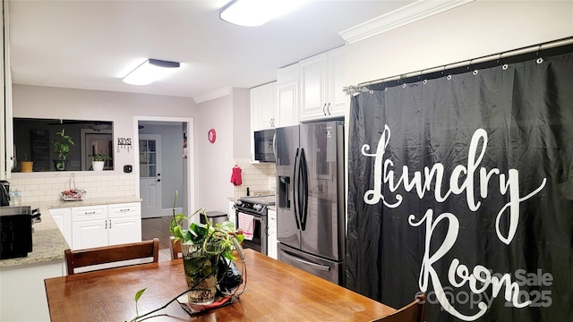 kitchen featuring tasteful backsplash, ornamental molding, stainless steel appliances, light stone countertops, and white cabinets