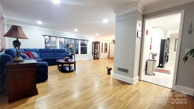 living room with ornamental molding and light hardwood / wood-style flooring