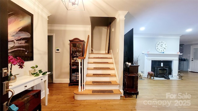 stairway featuring crown molding, decorative columns, and hardwood / wood-style flooring