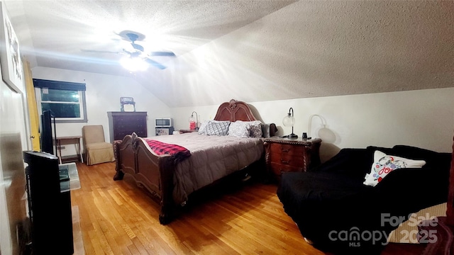 bedroom with hardwood / wood-style flooring, vaulted ceiling, and a textured ceiling