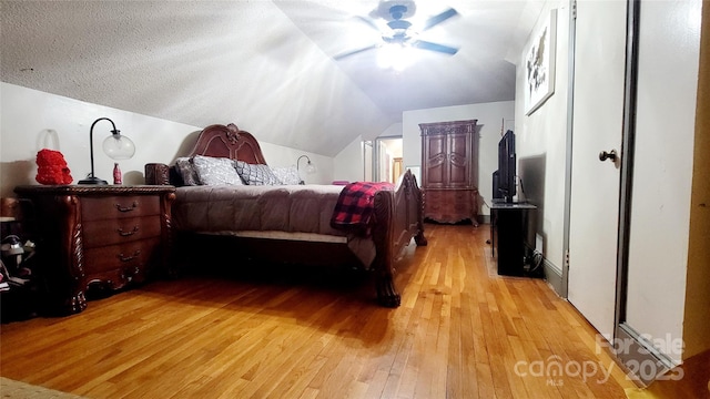 bedroom with vaulted ceiling, ceiling fan, a textured ceiling, and light hardwood / wood-style floors