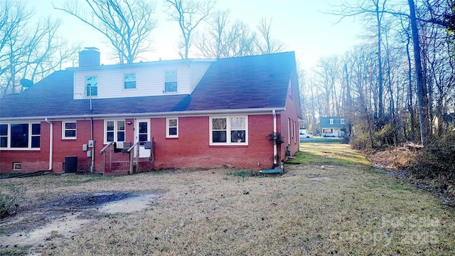 rear view of property featuring cooling unit and a lawn