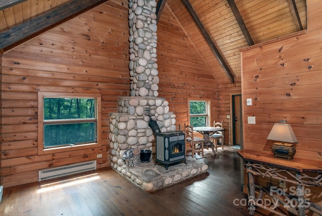 unfurnished living room featuring a baseboard radiator, beamed ceiling, a wood stove, and hardwood / wood-style flooring