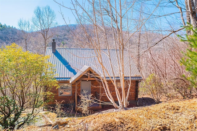 view of property exterior featuring a chimney and metal roof