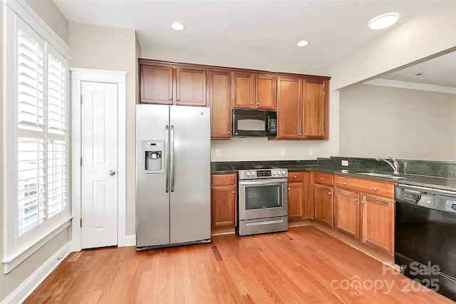 kitchen featuring sink, dark stone counters, light hardwood / wood-style floors, and black appliances