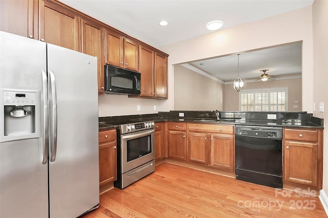 kitchen featuring sink, crown molding, black appliances, light hardwood / wood-style floors, and dark stone counters