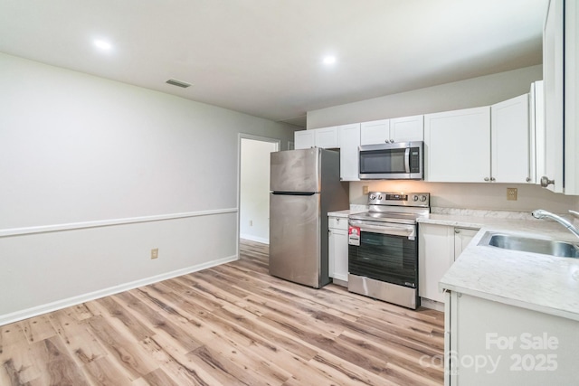 711 E John St, Matthews, NC 28105 - kitchen with appliances with stainless steel finishes, light countertops, light wood-type flooring, white cabinetry, and recessed lighting