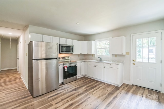 711 E John St, Matthews, NC 28105 - kitchen featuring appliances with stainless steel finishes, light wood-style floors, white cabinets, and light countertops