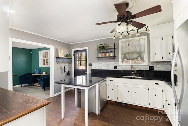 kitchen with appliances with stainless steel finishes, sink, white cabinets, kitchen peninsula, and dark wood-type flooring