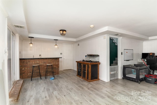 bar with hanging light fixtures and light hardwood / wood-style floors