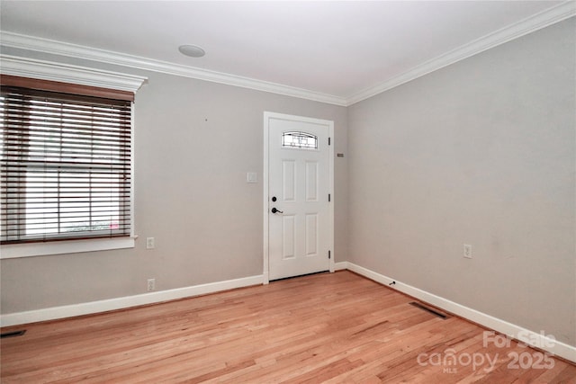 entryway with ornamental molding and light hardwood / wood-style floors