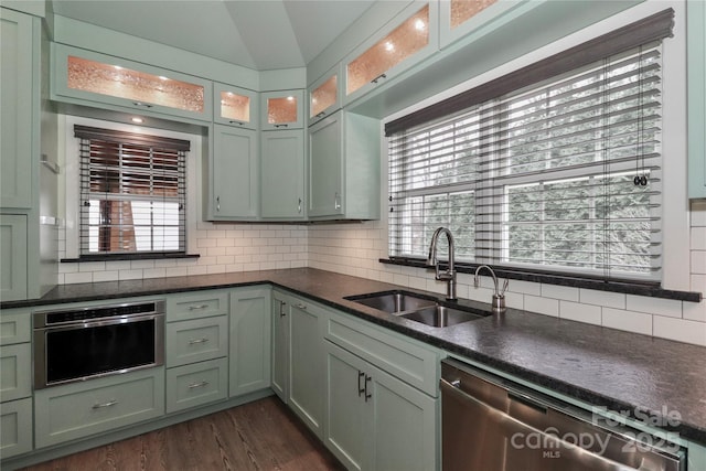 kitchen with vaulted ceiling, dark hardwood / wood-style floors, tasteful backsplash, dishwasher, and sink