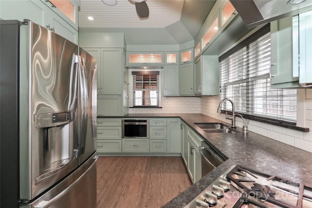 kitchen with sink, tasteful backsplash, dark stone countertops, appliances with stainless steel finishes, and dark hardwood / wood-style floors