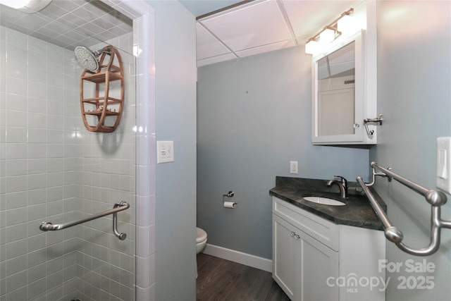 bathroom featuring tiled shower, wood-type flooring, toilet, and vanity