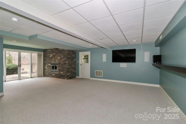 unfurnished living room with a large fireplace, a paneled ceiling, and carpet