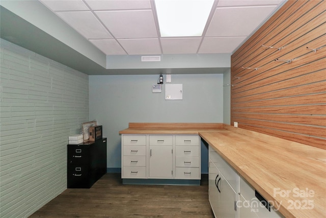 unfurnished office featuring dark wood-type flooring and a paneled ceiling