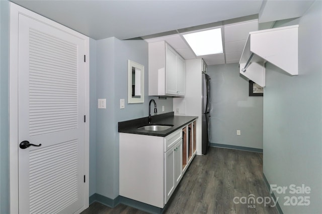 kitchen featuring sink, stainless steel fridge, white cabinets, dark hardwood / wood-style flooring, and a drop ceiling